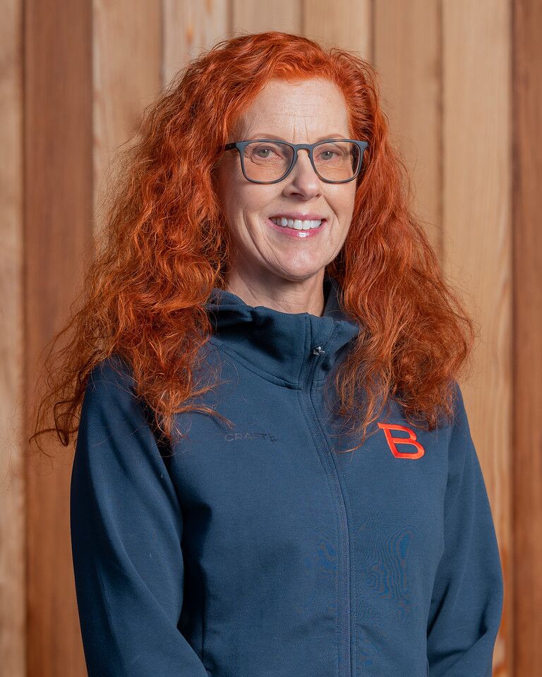 En kvinna med rött hår och glasögon i en Bergstrands hoodie