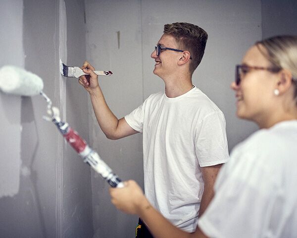 En man och kvinna som målar en vägg med en pensel.