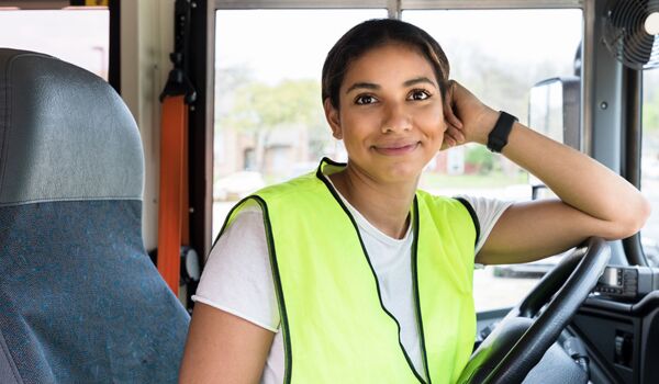 En kvinna som sitter i förarsätet på en buss.