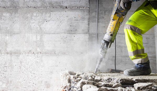Betongarbetare En byggnadsarbetare arbetar på ett betonggolv.